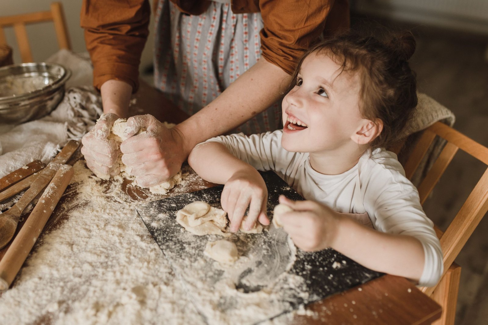 A young girl smiling while baking and kneading dough