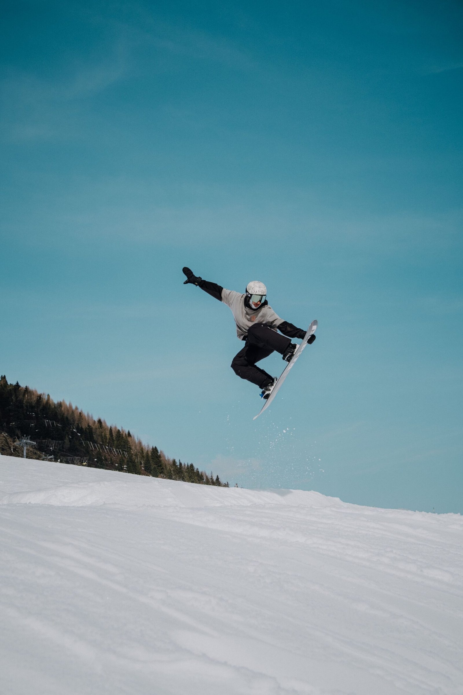 A snowboarder catching air mid-jump against a bright blue sky