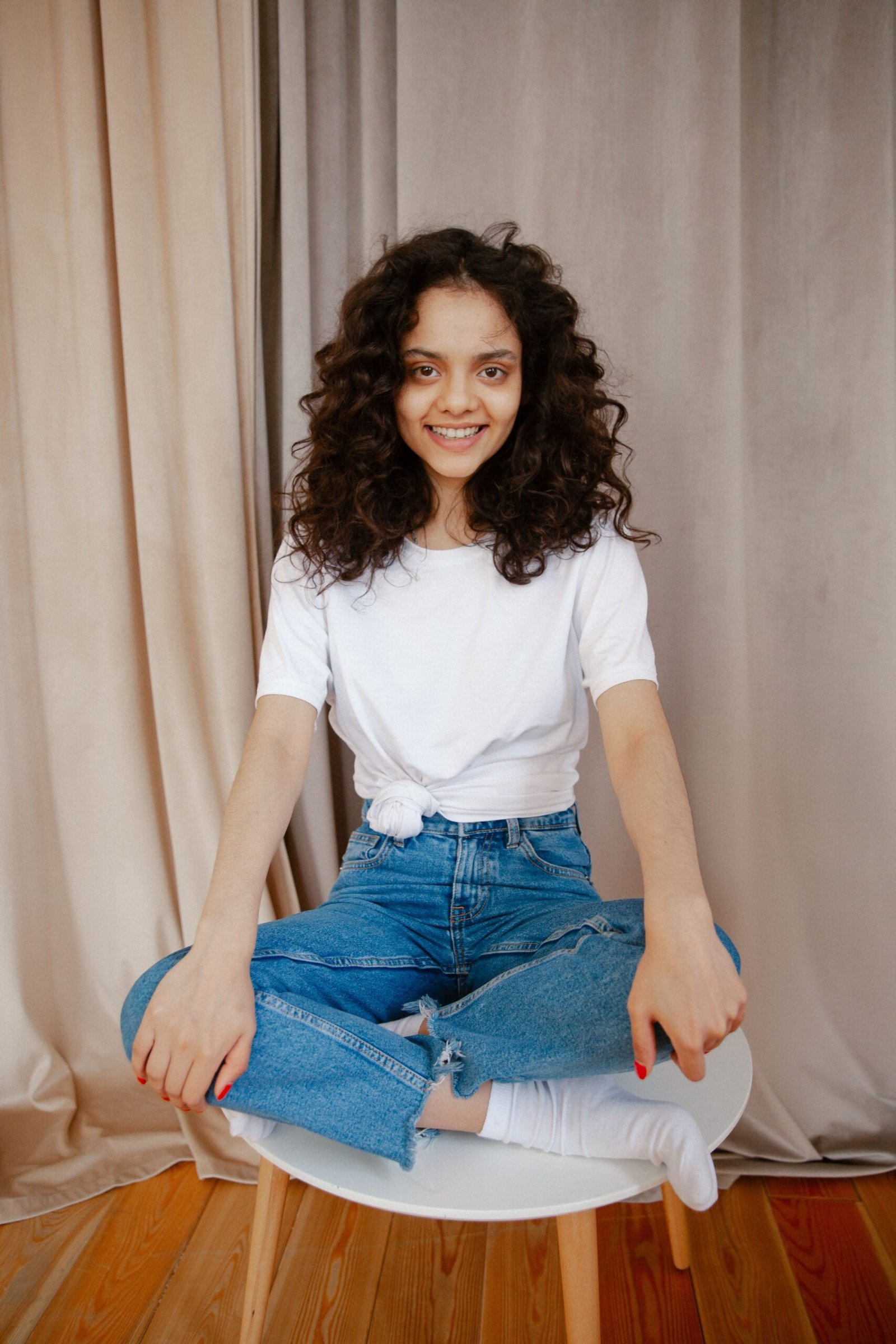 A smiling young woman with dark curly hair