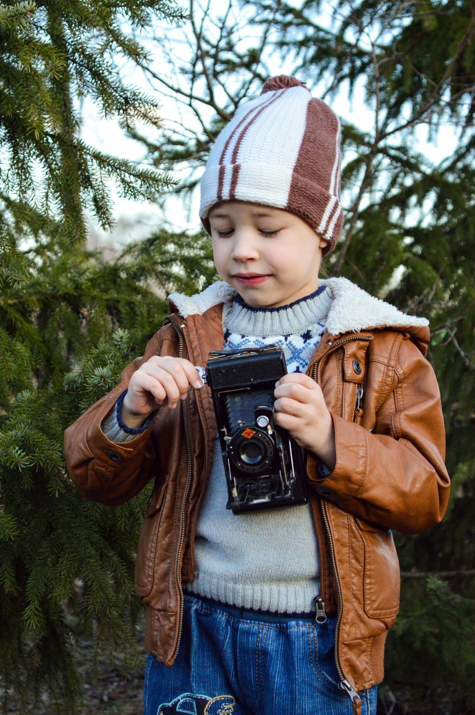 A young child wearing a winter hat and a brown jacket